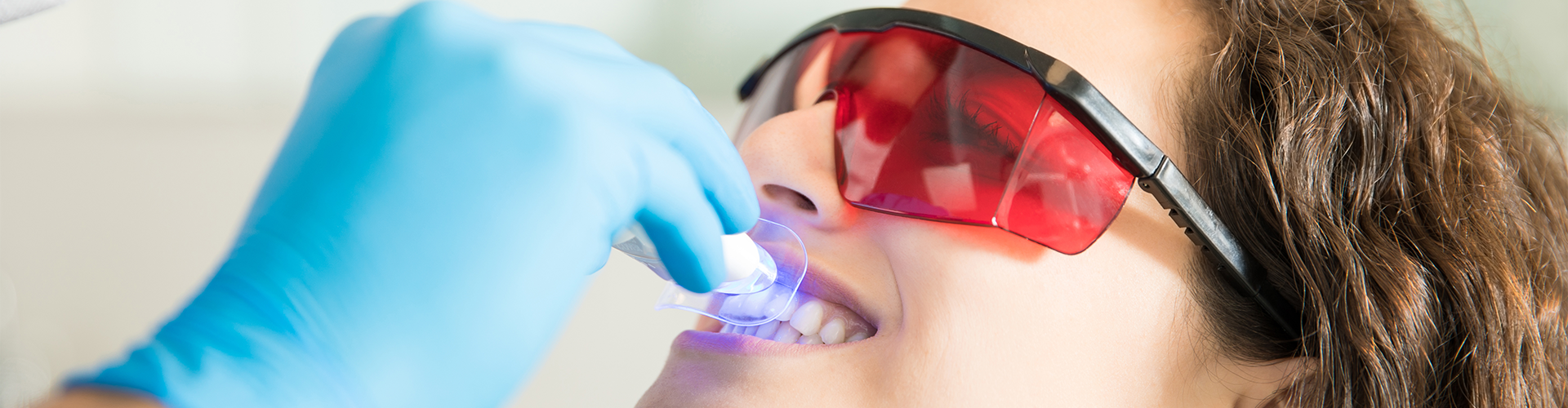 Dentist shining light onto woman's smile.